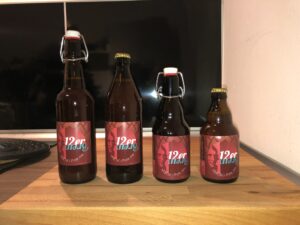 Frontprofil von 4 Bierflaschen in unterschiedlichen Größen mit Bügelverschluss oder Kronkorken. 2 Flaschen zu je 0,5 Liter und 2 Flaschen zu je 0,33 Liter